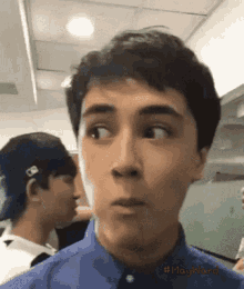 a man in a blue shirt is making a funny face while another man looks on