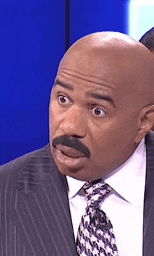 a bald man in a suit and tie is making a funny face .