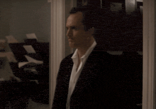 a man in a suit and tie walks past a stack of papers