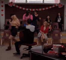 a group of people are dancing in a room decorated with hearts