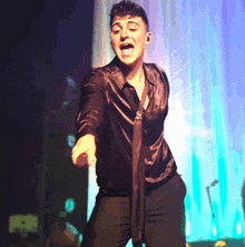a man in a black shirt is singing into a microphone on a stage
