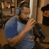 a man wearing headphones and a blue shirt is singing into a microphone