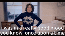 a man in a turtleneck sweater is standing in a bedroom with his hands on his hips