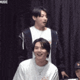 a group of young men are sitting next to each other and laughing in a room .