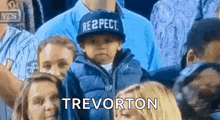a young boy wearing a hat that says respect is standing in a crowd .