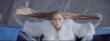 a woman in a white fur coat is sitting in a car .