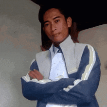 a man with his arms crossed wearing a blue jacket