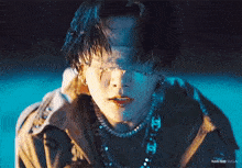a close up of a person wearing a jacket and a necklace .