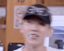 a man wearing a hat and goggles is brushing his teeth with a blue toothbrush .