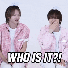 two boys are sitting next to each other and one of them is laughing and the other is saying who is it