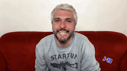 a man wearing a grey startup sweatshirt is smiling