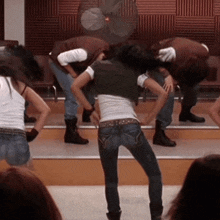 a group of people dancing in front of a fan