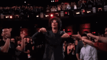 a man with glasses is dancing in front of a crowd of people