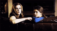 two women are sitting next to each other on a couch .