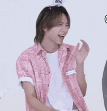 a young man wearing a pink plaid shirt with a name tag that says ' nct dream '