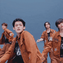 a group of young men are dancing and one of them is wearing a brown jacket