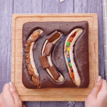 a person is holding a brownie with bananas and m & ms on it