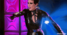 a woman in a black latex outfit is dancing in front of a purple star