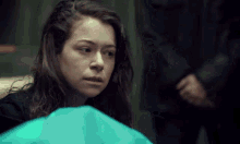 a woman is sitting next to a blue bag in a room .