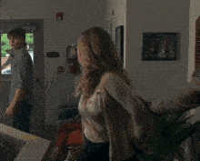 a woman walking in a hallway with a fire extinguisher on the wall