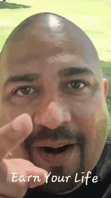 a man with a beard is pointing at the camera with the words " earn your life " written below him