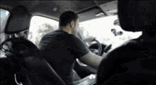 a man is driving a car with another man sitting in the back seat .