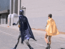 batman and robin are walking down a street in front of a building