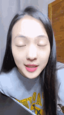 a woman with her eyes closed wearing a shirt that says nautica