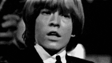 a black and white photo of a young man in a suit and tie making a surprised face .