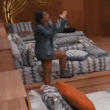 a woman in a blue dress is standing on a bed in a bedroom .