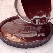 chocolate sauce is being poured into a chocolate tart