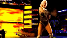a woman in a wrestling outfit is dancing on a stage in front of a yellow background .