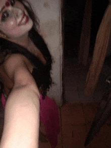 a woman in a pink dress is taking a selfie with her arm outstretched .
