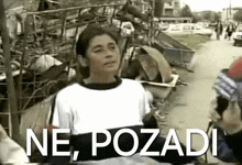 a woman in a white shirt stands in front of a pile of trash and the words ne pozadi