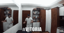 a man is dancing in front of a mirror and the word vitoria is on the wall
