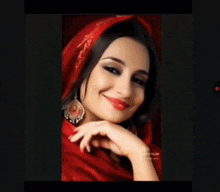 a woman wearing a red scarf and earrings smiles for the camera .