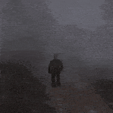 a man is walking through a foggy forest near a cross .