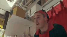 a man dressed as an elf is standing in front of a shelf with a sign that says ' amanda ' on it