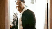 a man in a denim jacket is standing in a doorway and looking at the camera .