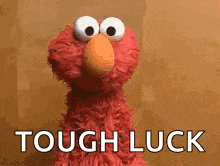 elmo from sesame street is saying `` tough luck '' while standing in front of a brown background .