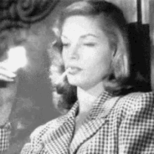 a woman is smoking a cigarette while wearing a plaid jacket .