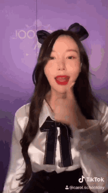 a woman wearing a white shirt with a black bow on her head .