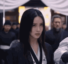 a woman with long black hair is standing in front of a crowd .