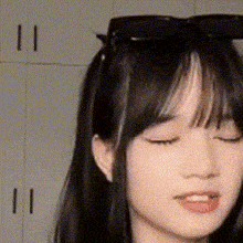 a close up of a woman wearing sunglasses and making a funny face with her eyes closed .