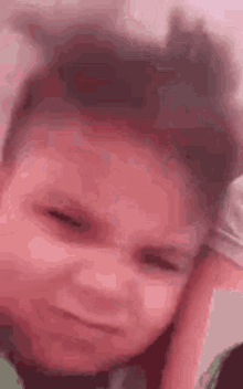 a young boy is making a funny face with his eyes closed .