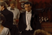 a man in a tuxedo and bow tie is standing in front of a sign that says ' port clare '