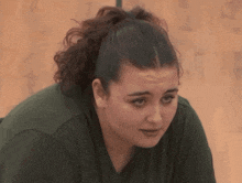 a woman with a ponytail and a green shirt is looking down