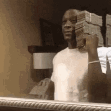 a man is standing in front of a mirror holding a large stack of money .