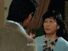 a man and a woman are looking at each other with chinese writing on the screen