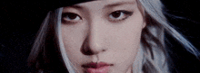 a close up of a woman 's face with a hat on and piercings in her nose .